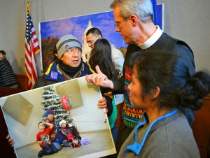 Luis Enrique Gomez, holding a picture of his children, talks with Rev. Paul Erickson.