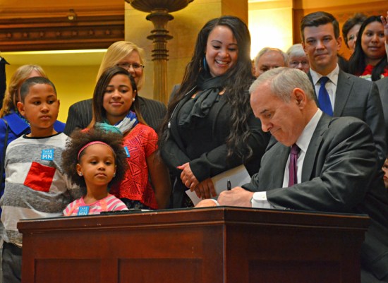 Surrounded by legislative supporters and members of the Raise the Wage Coalition, Minnesota Gov. Mark Dayton signed a bill increasing the minimum wage to $9.50 by 2016 – and indexing it to inflation.