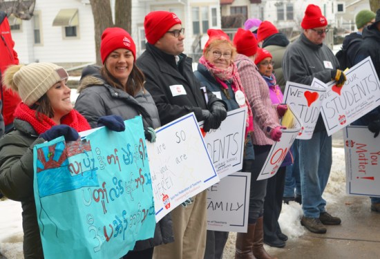 Leah Adair, a teacher at Crossroads Montessori in St. Paul, holds a sign reading "You are welcome here and safe here" in Karen.